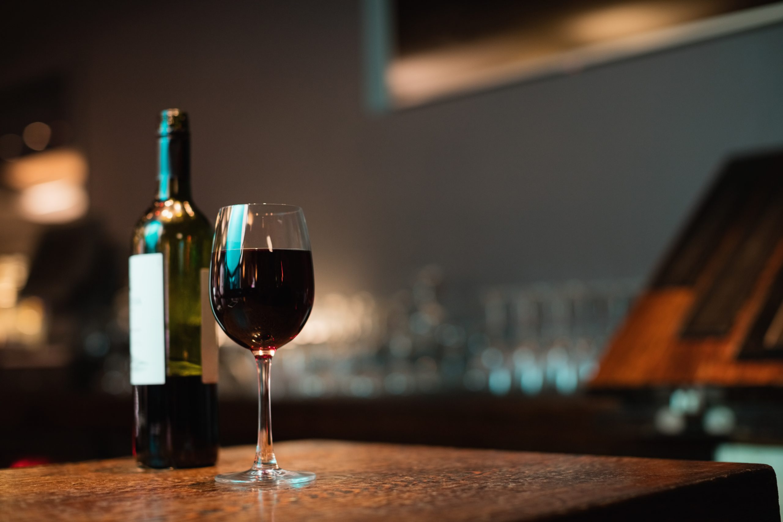 Glass of red wine and bottle on bar counter at bar