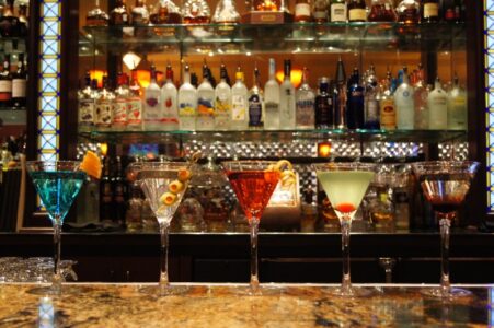 Four martini glasses sitting on a marble bar at Kirby's Steakhouse in San Antonio waiting for Happy Hour