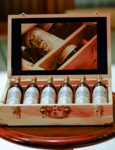 Six bottles of wine in a wood box with a mirror on the lid