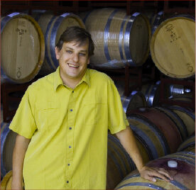 Zach Winemaker with barrels of wine