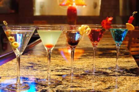 four drinks in martini glasses on the bar for Kirby's Steakhouse Happy Hour